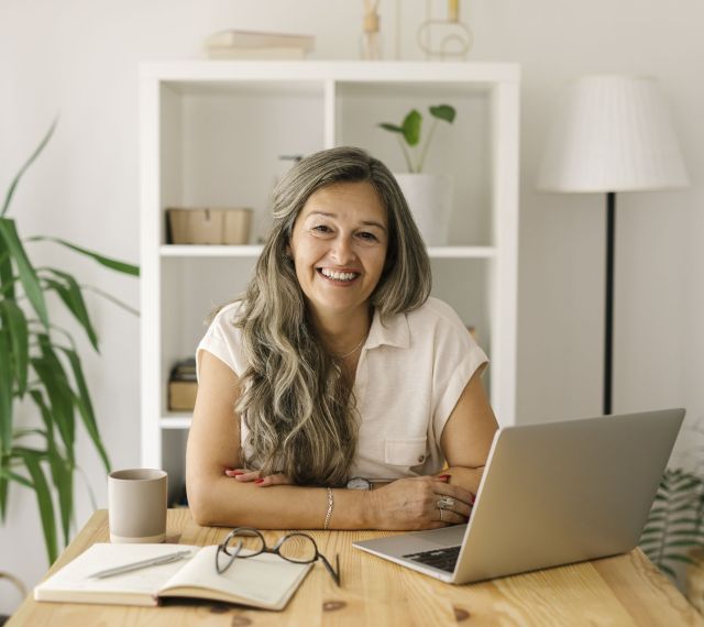 Frau sitzt mit Laptop an ihrem Schreibtisch